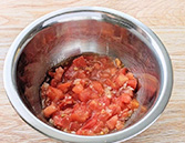 トボウルにトマトを入れ、塩1つまみを加えて混ぜる様子